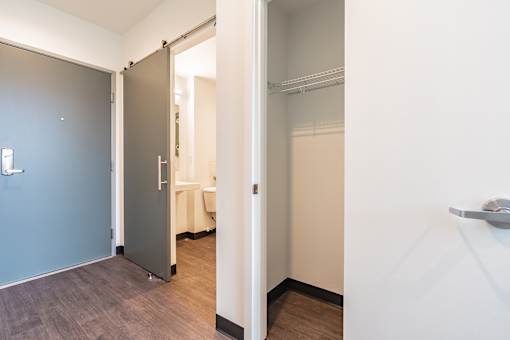 A white door is open to a room with a bed.