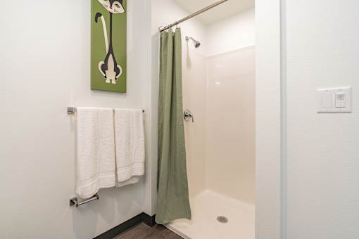 A bathroom with a green shower curtain and a white towel hanging on a rack.