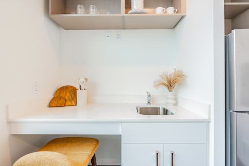 A kitchen with a white counter and a yellow chair.