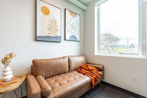 A brown leather couch with a small table beside it.