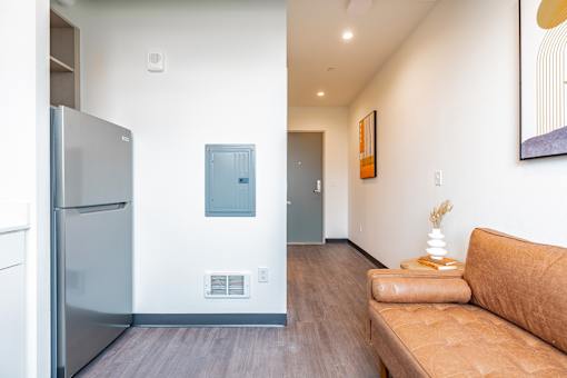 A modern kitchen with a refrigerator, a couch, and a painting on the wall.