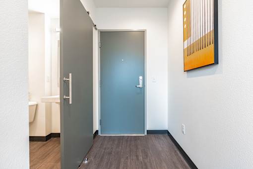 A hallway with a blue door and a painting on the wall.