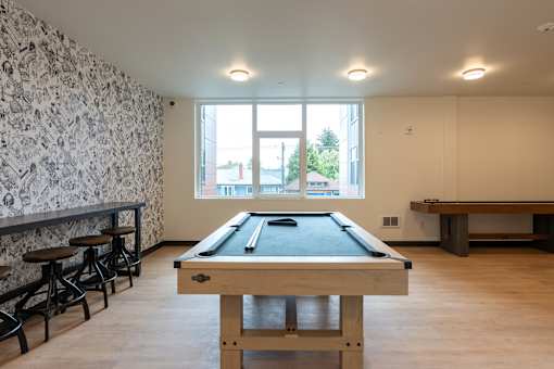 A pool table in a room with a bar and a window.