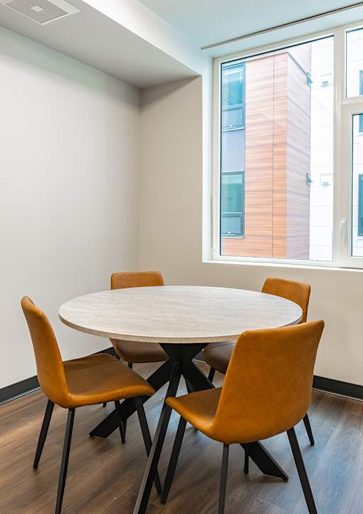 A white table with four chairs in front of a window.