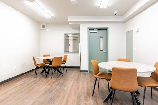 A conference room with a white table and brown chairs.