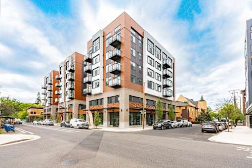 A modern apartment building with a parking lot in front.