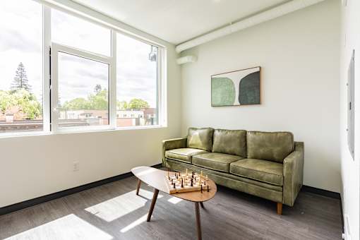A living room with a green couch and a chess set on the table.