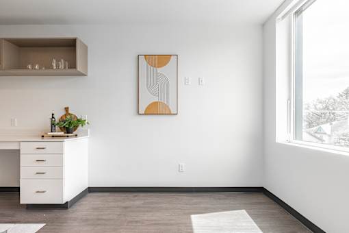 A modern kitchen with a white desk and a painting on the wall.