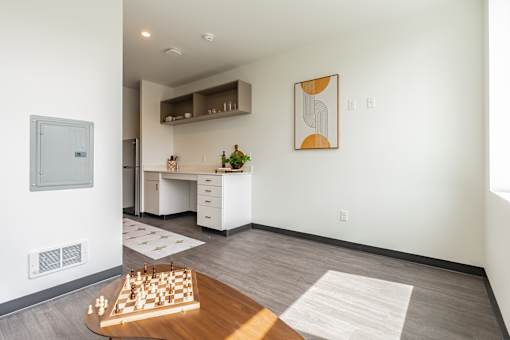 A chess board is on a wooden table in a white room.