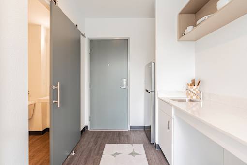 A kitchen with a sink, refrigerator, and a door.