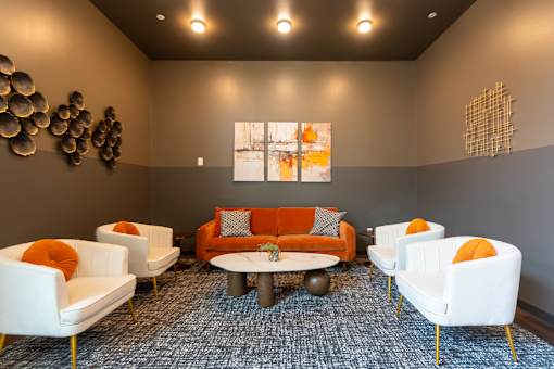 A living room with white chairs and an orange couch.