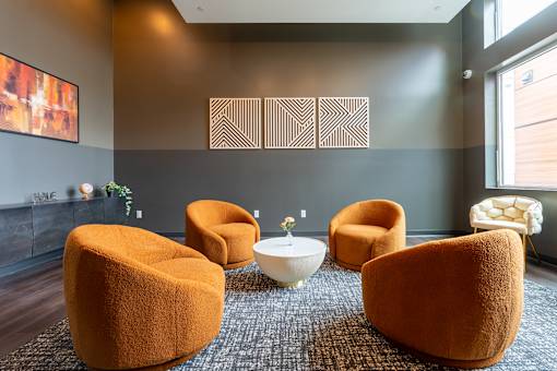 A room with orange chairs and a white table.