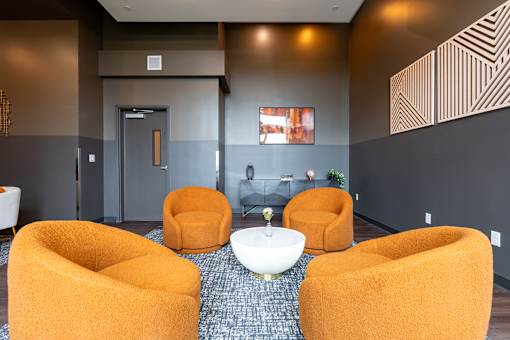 A room with orange chairs and a white table.