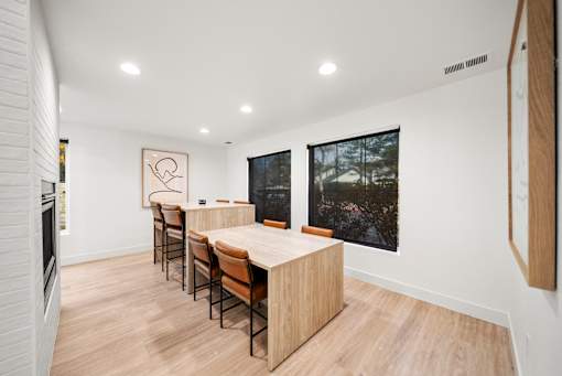 A long wooden table with chairs is in a white room.