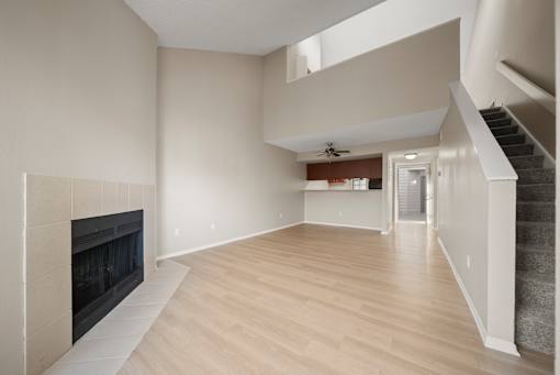 A spacious living room with a fireplace and a staircase.