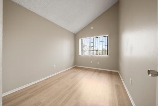 Empty room with a window and wooden flooring.