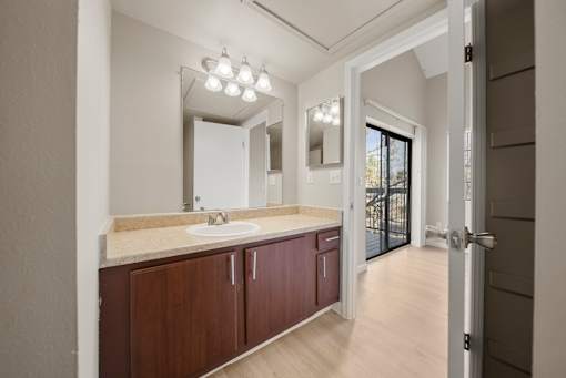A bathroom with a sink, mirror, and wooden cabinets.