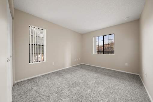 A room with a carpeted floor, a window with bars, and a door.