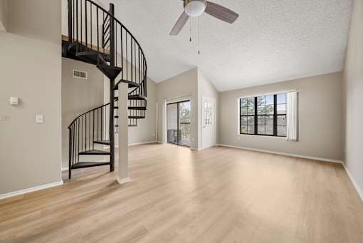 A spacious room with a spiral staircase and a ceiling fan.