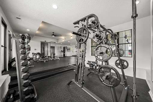 A black and white photo of a home gym with a squat rack and weights.