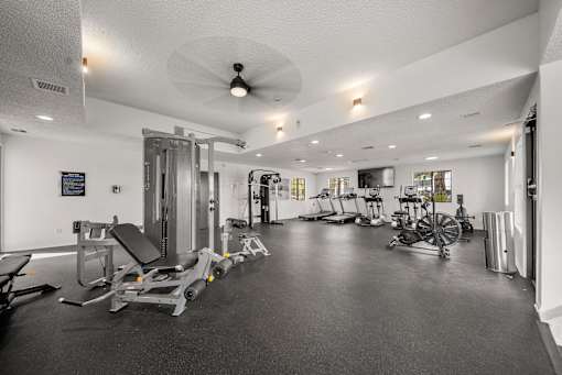 A spacious gym with a variety of equipment including treadmills, stationary bikes, and weight machines.
