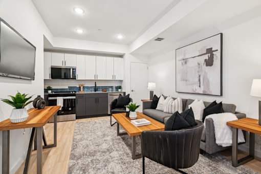 A modern living room with a grey couch, a wooden coffee table, and a television on the wall.