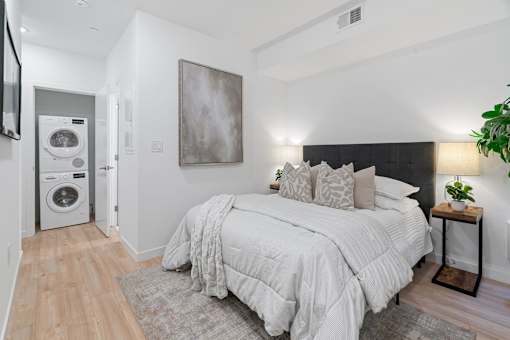 A bedroom with a large bed and a washing machine in the corner.