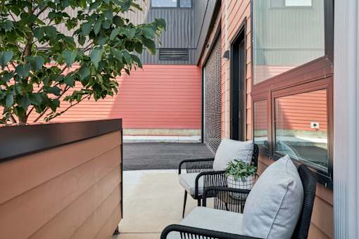 A patio with a chair and a table with a plant on it.
