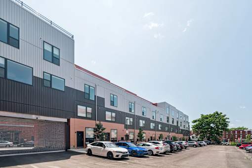 A parking lot with cars and a building with a red stripe.