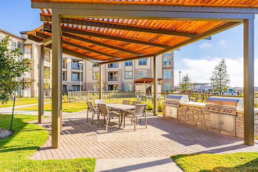 A patio with a table and chairs under a pergola.