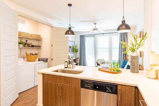 A kitchen with a stainless steel dishwasher and wooden cabinets.