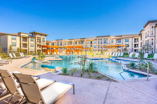 A pool surrounded by chairs and buildings.