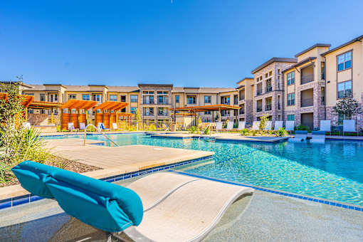 A poolside lounge chair overlooks a swimming pool at a resort.