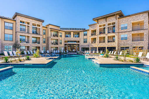 A large swimming pool in front of a multi-story residential building.
