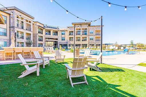 A sunny day at a poolside with lawn chairs and a building in the background.