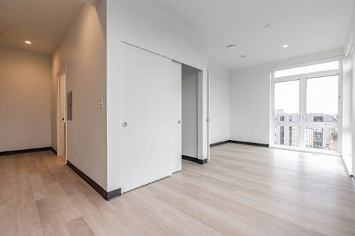 A room with a white door and a window with a view of buildings outside.