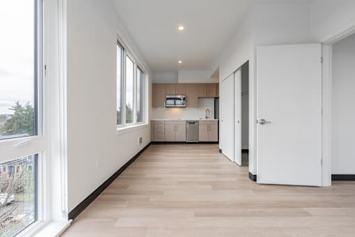 A long, empty hallway with white walls and wood flooring.