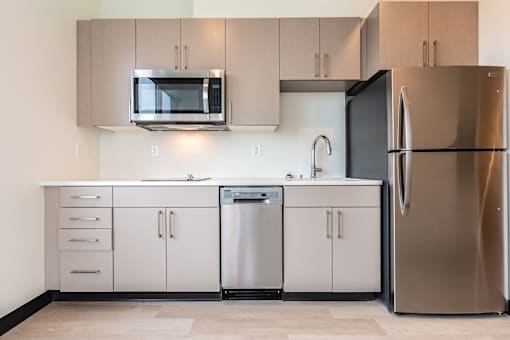 A modern kitchen with a stainless steel refrigerator, microwave, dishwasher, and cabinets.