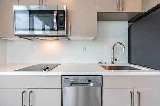 A modern kitchen with a stainless steel dishwasher and a black refrigerator.