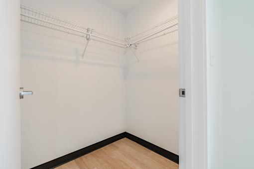 A white wall with a door and a wooden floor.