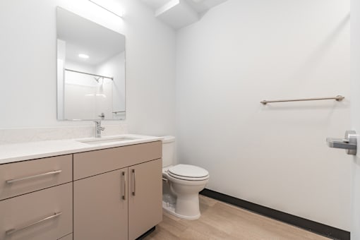A bathroom with a toilet, sink, and mirror.