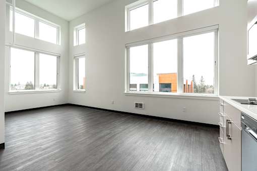 A large empty room with a kitchen area to the right.
