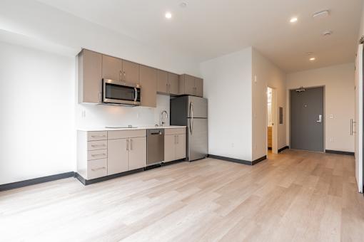 A kitchen with a microwave, refrigerator, and cabinets.