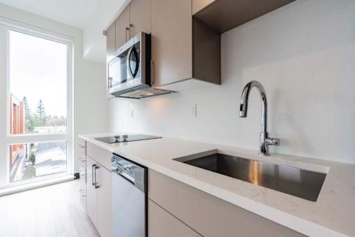 A modern kitchen with a stainless steel sink and a microwave above the stove.