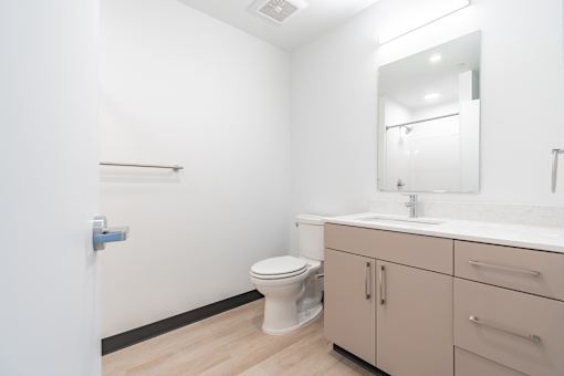 A white bathroom with a toilet, sink, and mirror.