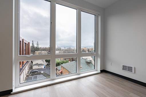 A room with a large window overlooking a parking lot and buildings.