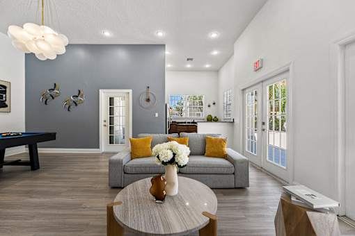 Kissimmee, FL Townhomes for Rent - Estates at Lake Cecile – A modern clubhouse with a grey couch and a coffee table.