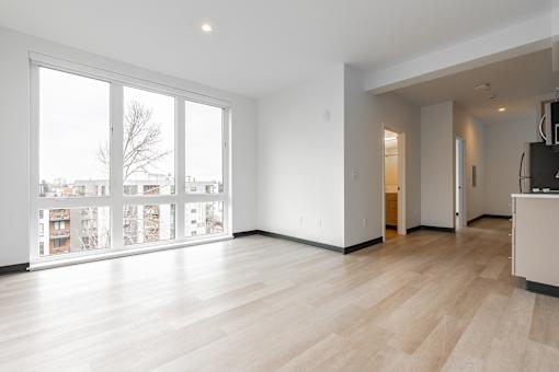 A spacious room with a large window and wooden flooring.