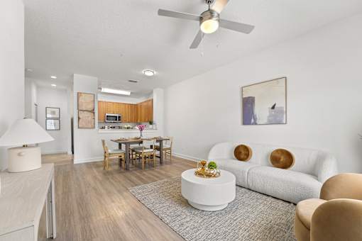 Three- & Four-Bedroom Townhomes in Kissimmee, FL - Estates at Lake Cecile – A living room with a white couch and a wooden dining table.