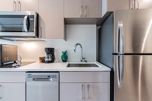 A modern kitchen with a stainless steel refrigerator and white cabinets.